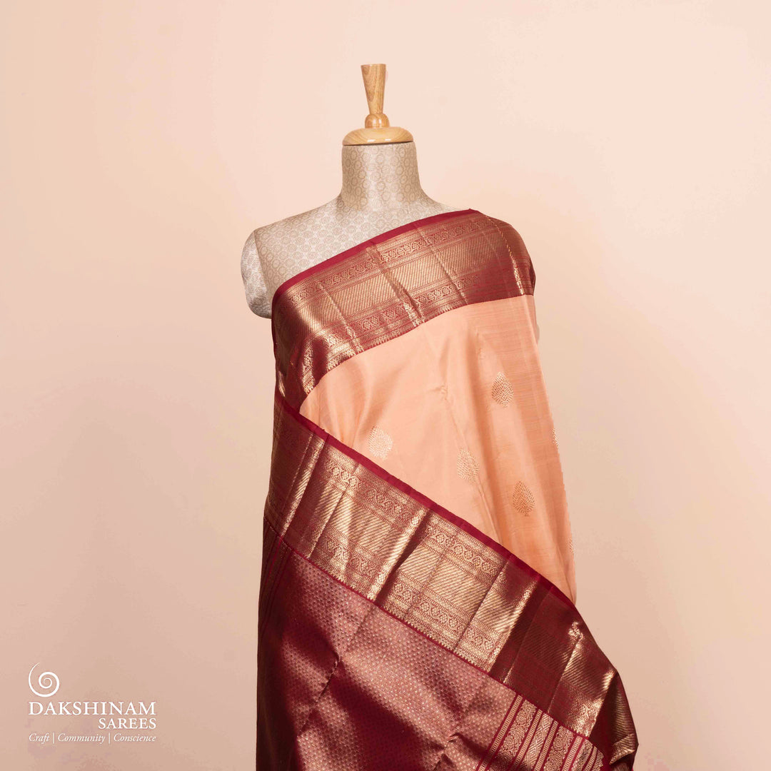 Full view of a Peach Kanjivaram silk saree with maroon korvai border.