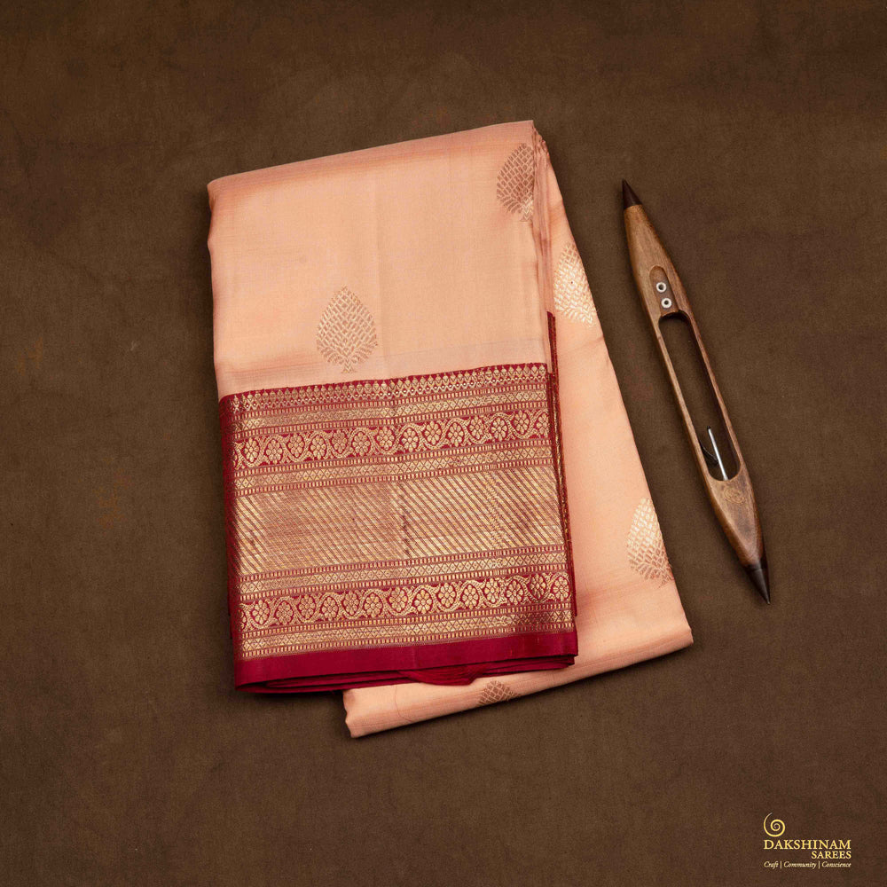 Closeup view of a Peach Kanjivaram silk saree with maroon korvai border.