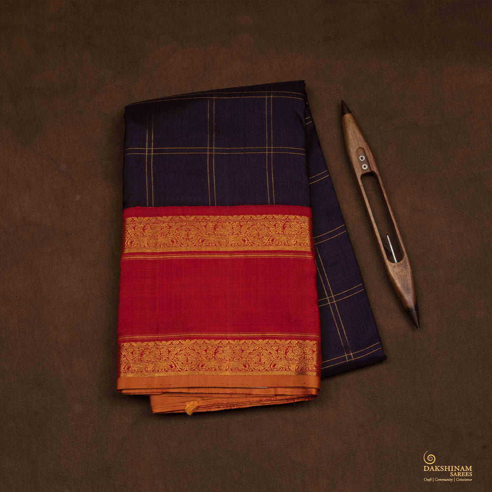 Closeup view of a Midnight blue Kanjivaram silk saree with red korvai border and gold checks.