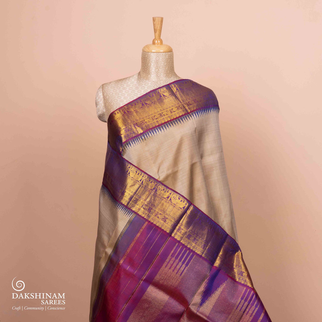 Full view of a Beige Kanjivaram silk saree with magenta korvai temple border.