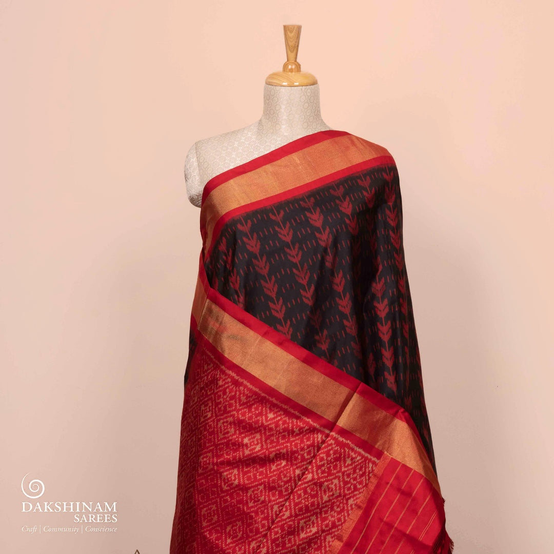 Full view of a Black Ikat silk saree with red border and floral diamond pallu.