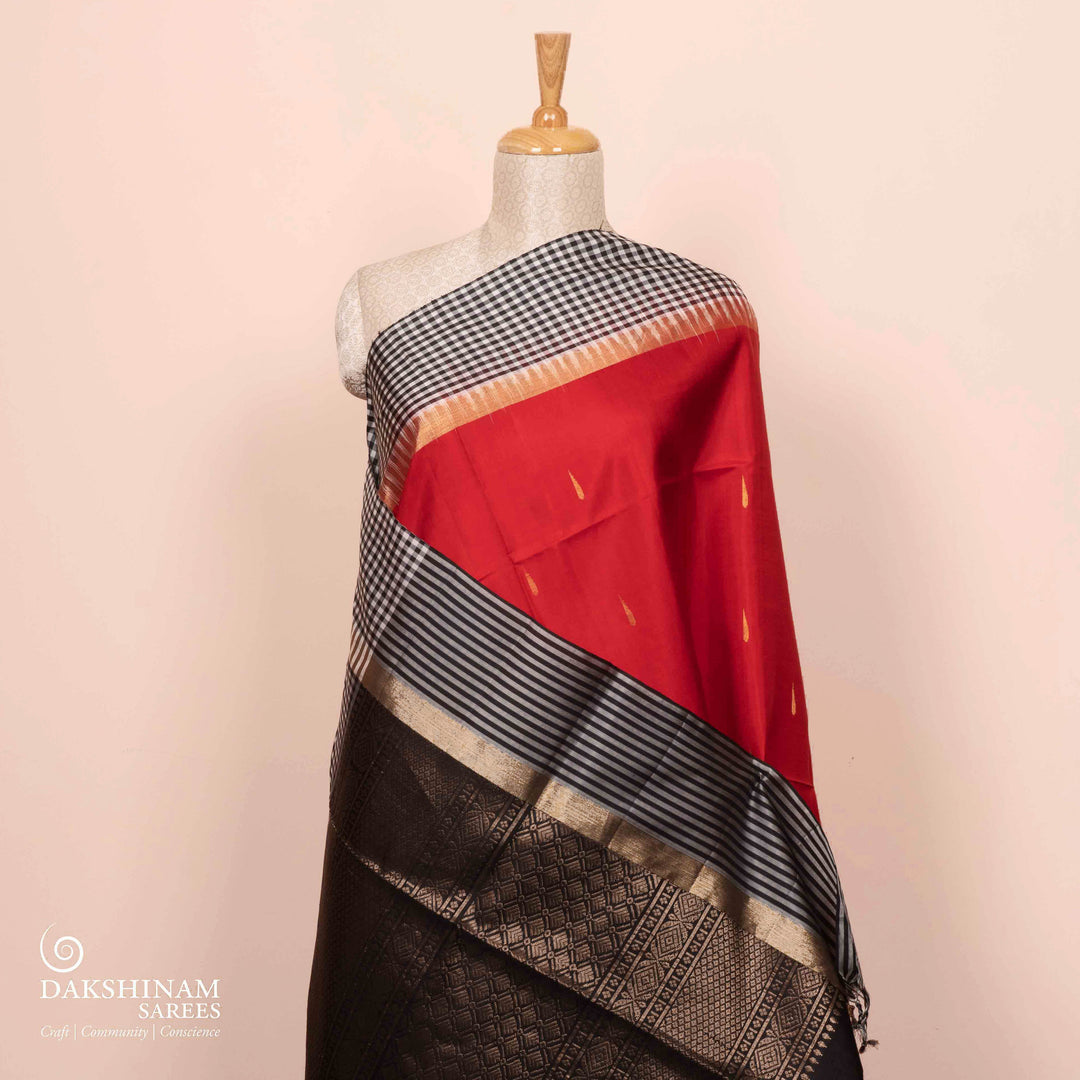 Full view of a Red soft silk saree with black border and zari buttas.