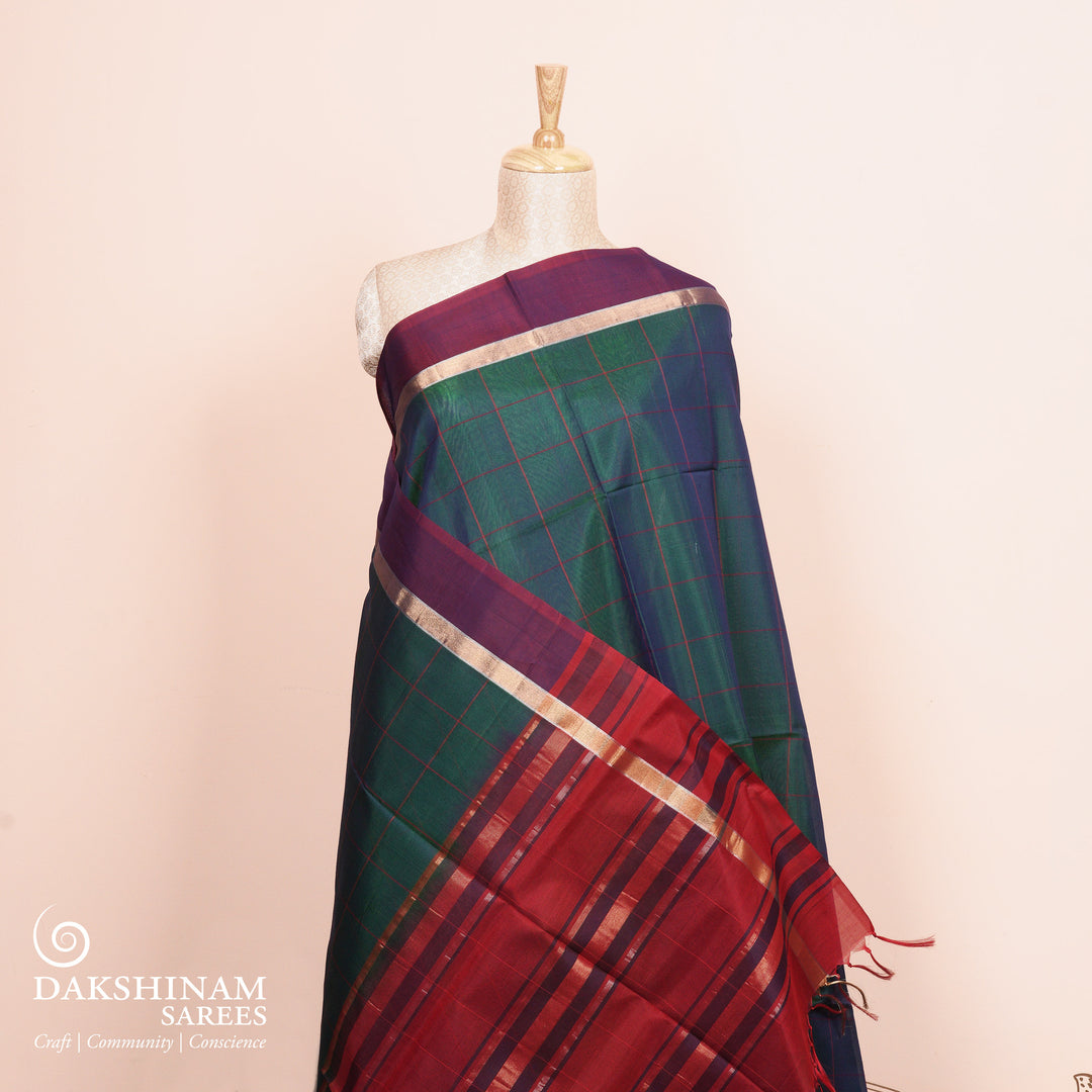 Full view of a Peacock blue silk cotton saree with wine border and red zari pallu.