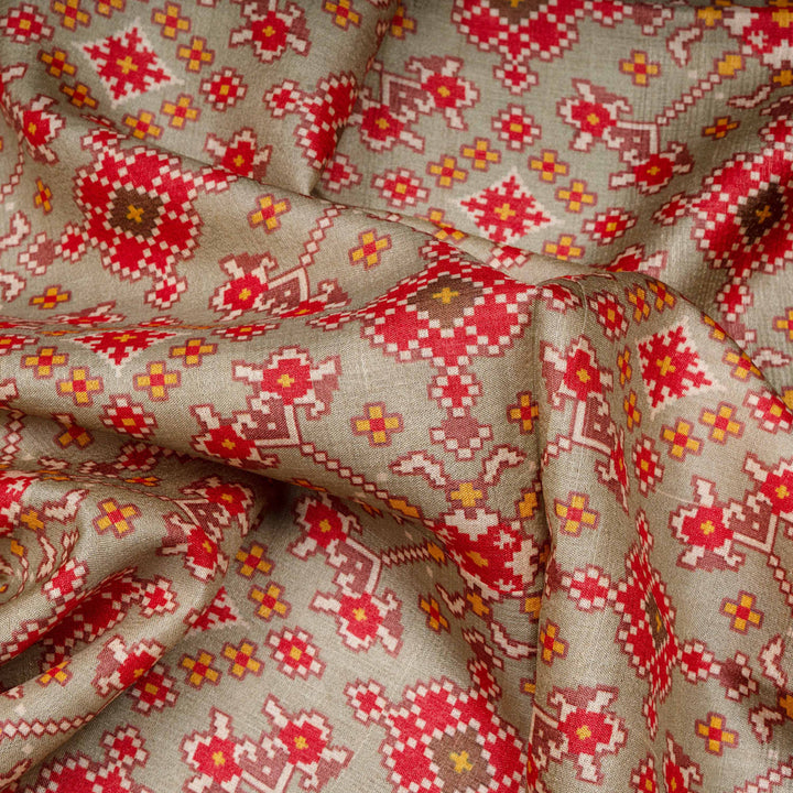 Close-up of patterned fabric with red, orange, and brown colors on a beige background