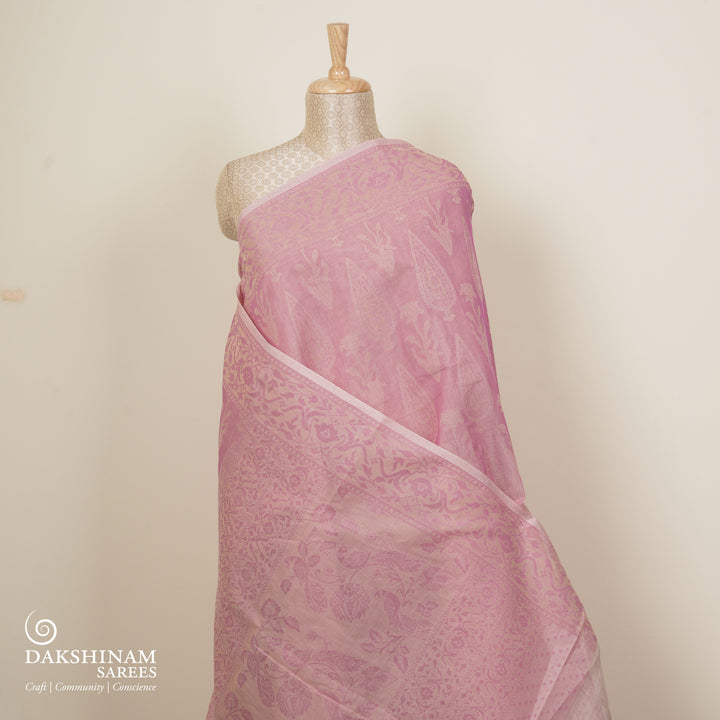 Pink South cotton saree with plant and paisley motifs across the body, floral border and peacock motif pallu, matching blouse with diamond butta design.