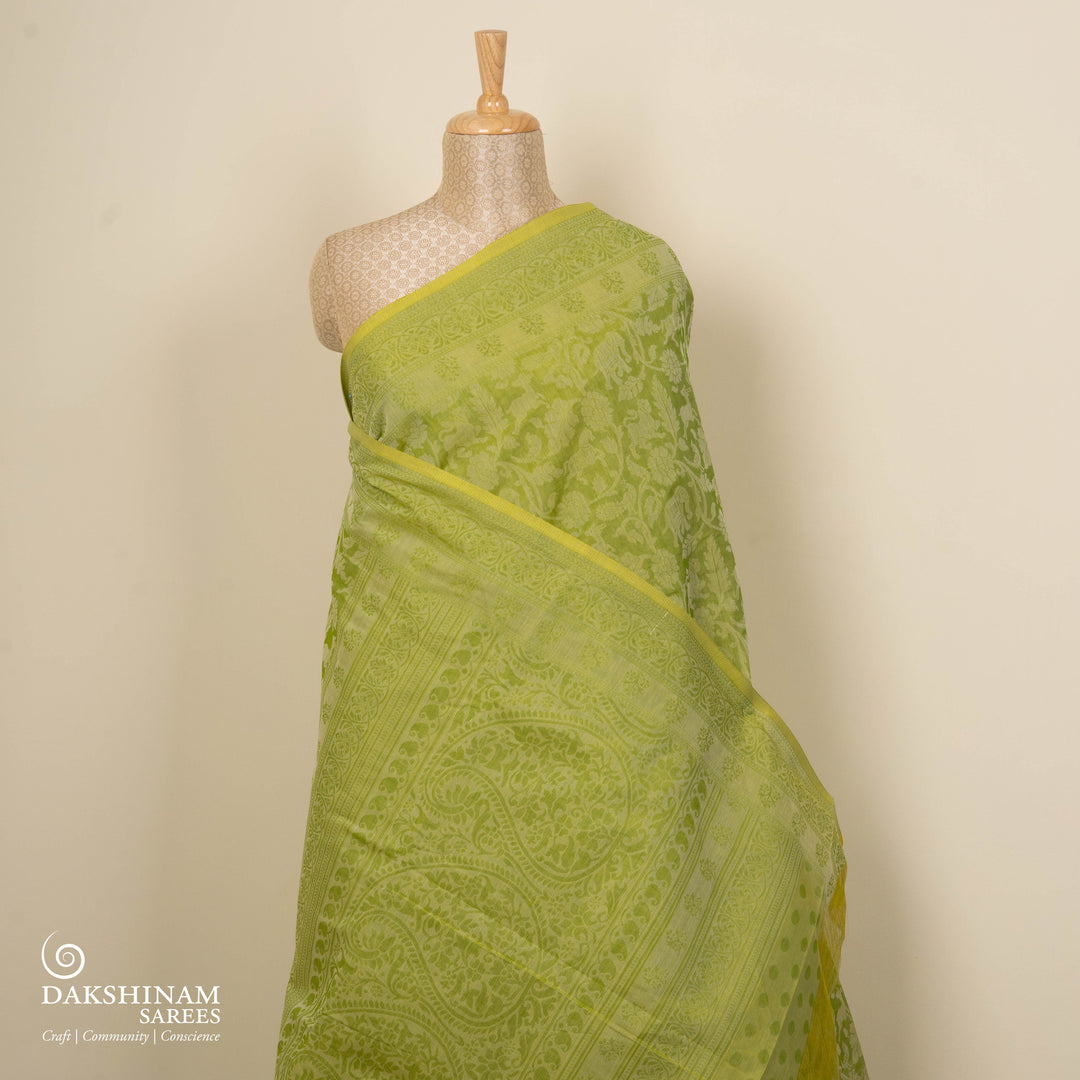 Lime green South cotton saree with floral body featuring peacock, horse, elephant, deer and tiger motifs, traditional border and paisley pallu, matching blouse with dot design.