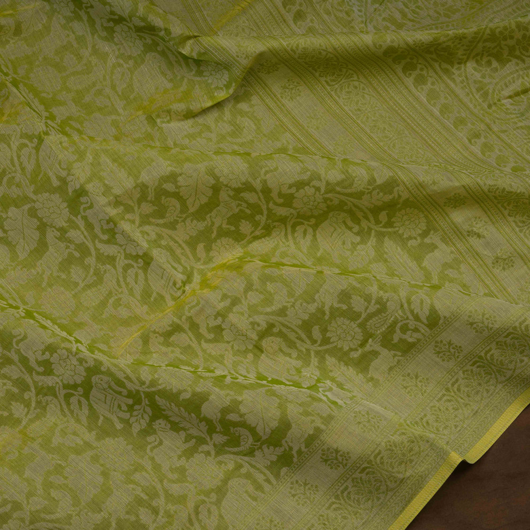 Lime green South cotton saree with floral body featuring peacock, horse, elephant, deer and tiger motifs, traditional border and paisley pallu, matching blouse with dot design.