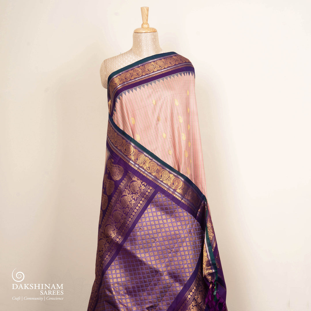 Peach Gadwal silk saree with grey checks and small butta body, purple zari border with mango and leaf motifs, plain purple blouse.