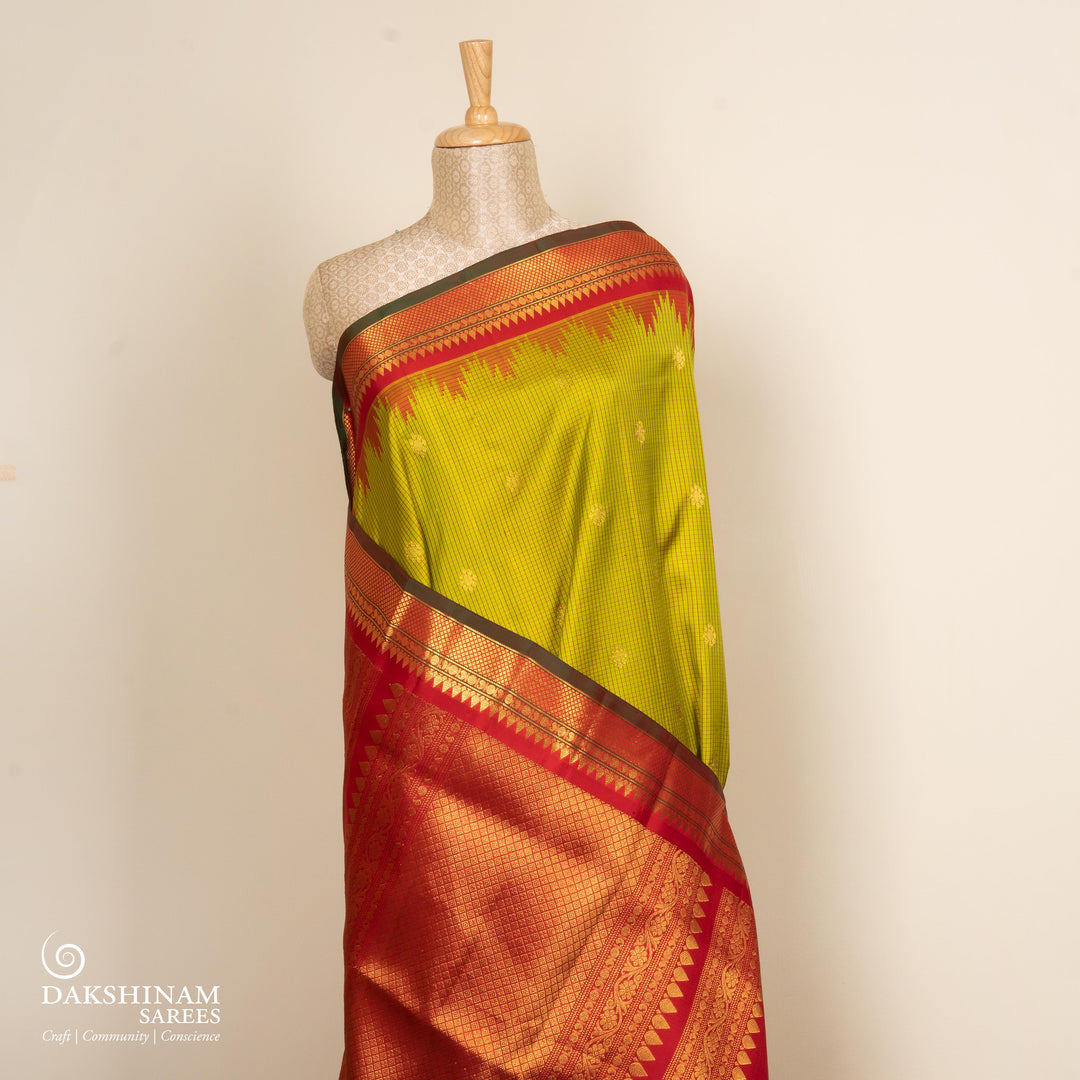 Lime green Gadwal silk saree with red check lines and small butta body, red zari border with rudraksh and mango motifs, plain red blouse.