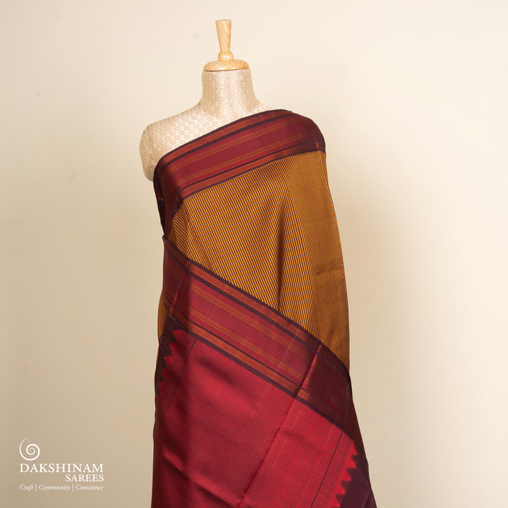 Mustard Gadwal silk saree with brown micro checks body, contrasting woven border with stripes and diamond patterns, brown pallu with temple motifs.