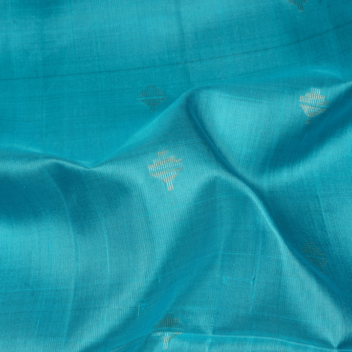 Light blue soft silk saree with silver butta allover, pink and gold zari border and pink pallu with bird and plant motifs.