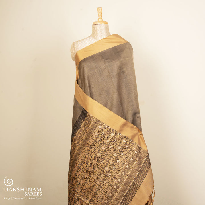 Beige soft silk saree with self-textured body, plain border and beige pallu with floral vine, lotus and chevron motifs in black and gold zari, paired with black blouse.