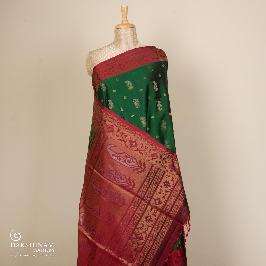 Green soft silk saree with paisley leaf buttas in gold and silver zari, maroon Paithani style border with floral vines and maroon pallu with paisley motifs.