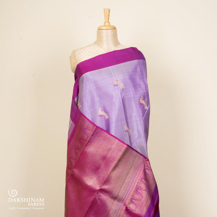 Purple handwoven Kanjivaram silk saree with meenakari parrot motifs, magenta border, detailed pallu with mango, thazampoo, and temple designs, paired with magenta blouse.