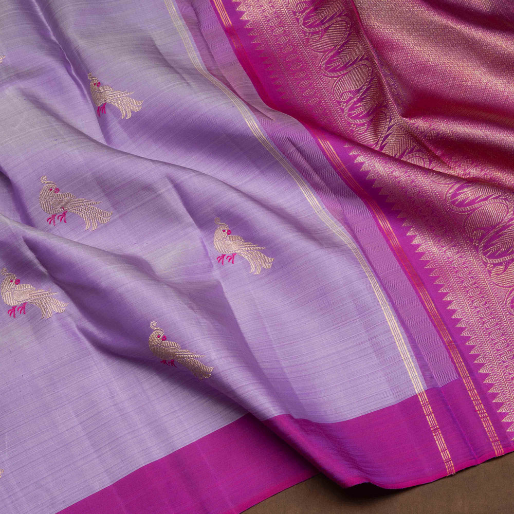 Purple handwoven Kanjivaram silk saree with meenakari parrot motifs, magenta border, detailed pallu with mango, thazampoo, and temple designs, paired with magenta blouse.