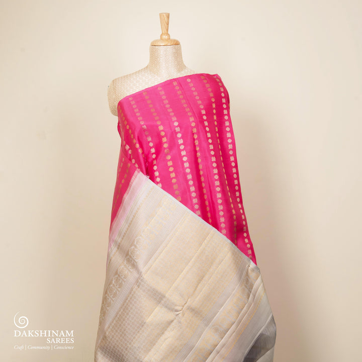 Pink handwoven Kanjivaram silk saree with vertical annam and chakram zari buttas, grey pallu with floral and traditional motifs, paired with grey blouse.