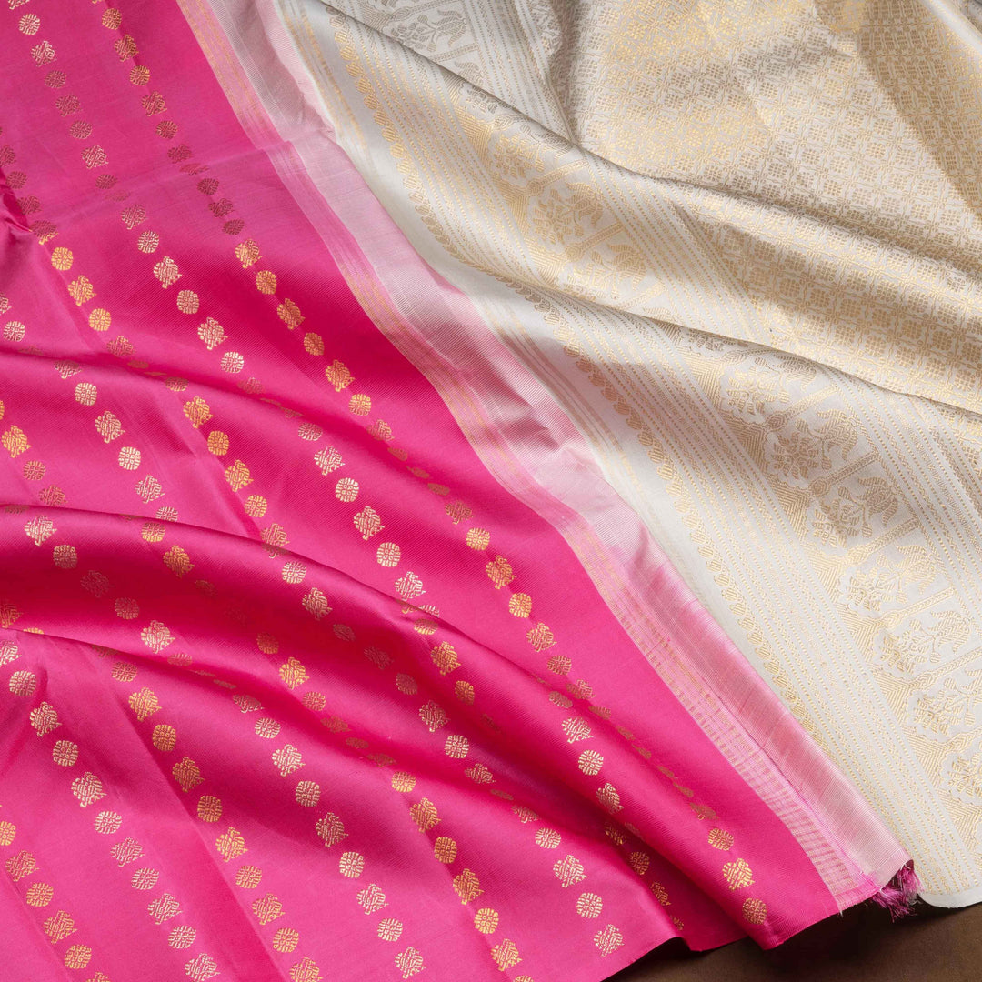 Pink handwoven Kanjivaram silk saree with vertical annam and chakram zari buttas, grey pallu with floral and traditional motifs, paired with grey blouse.