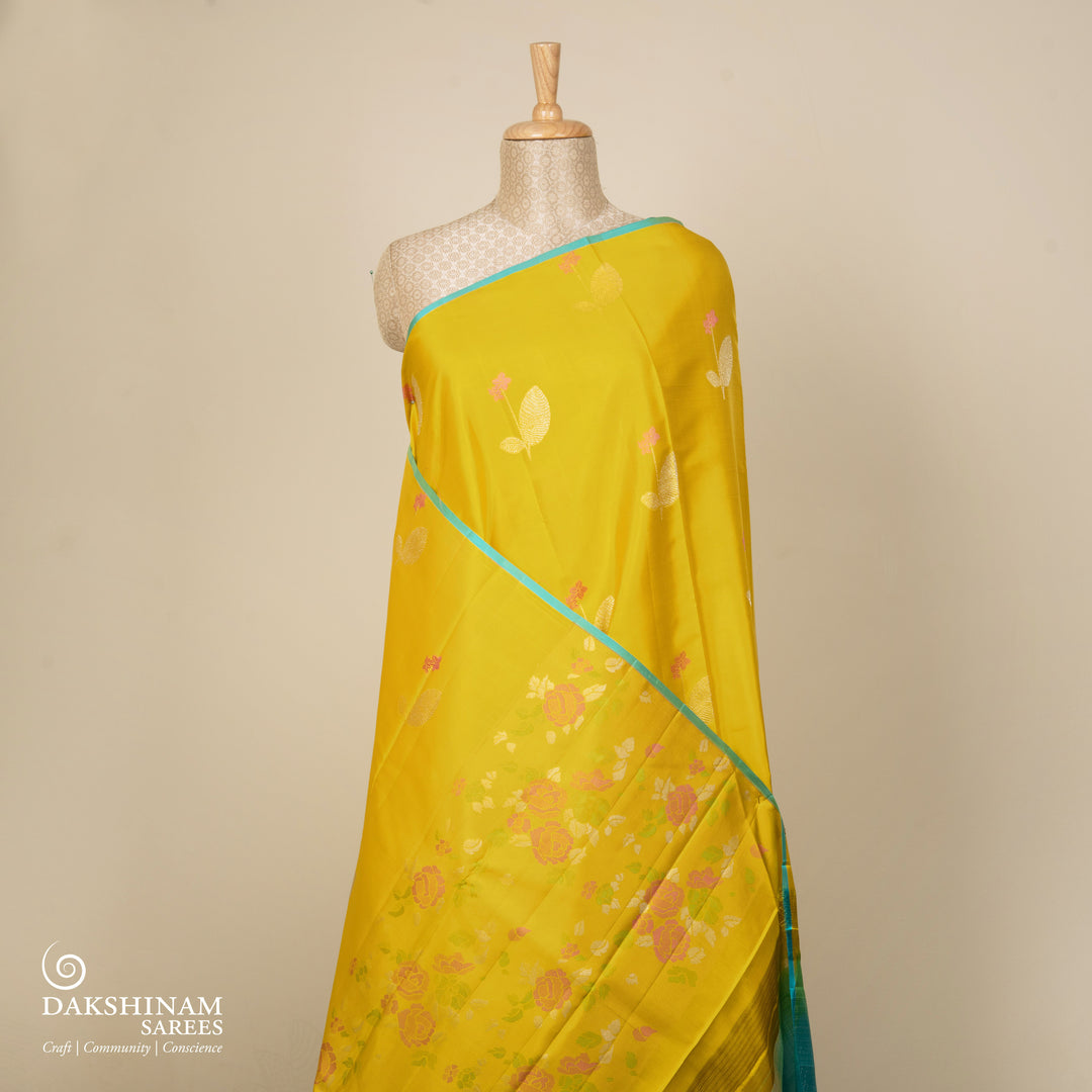 Lime green handwoven Kanjivaram silk saree with floral and leaf motifs, rose design pallu, borderless style, paired with light blue blouse with silver zari stripes.