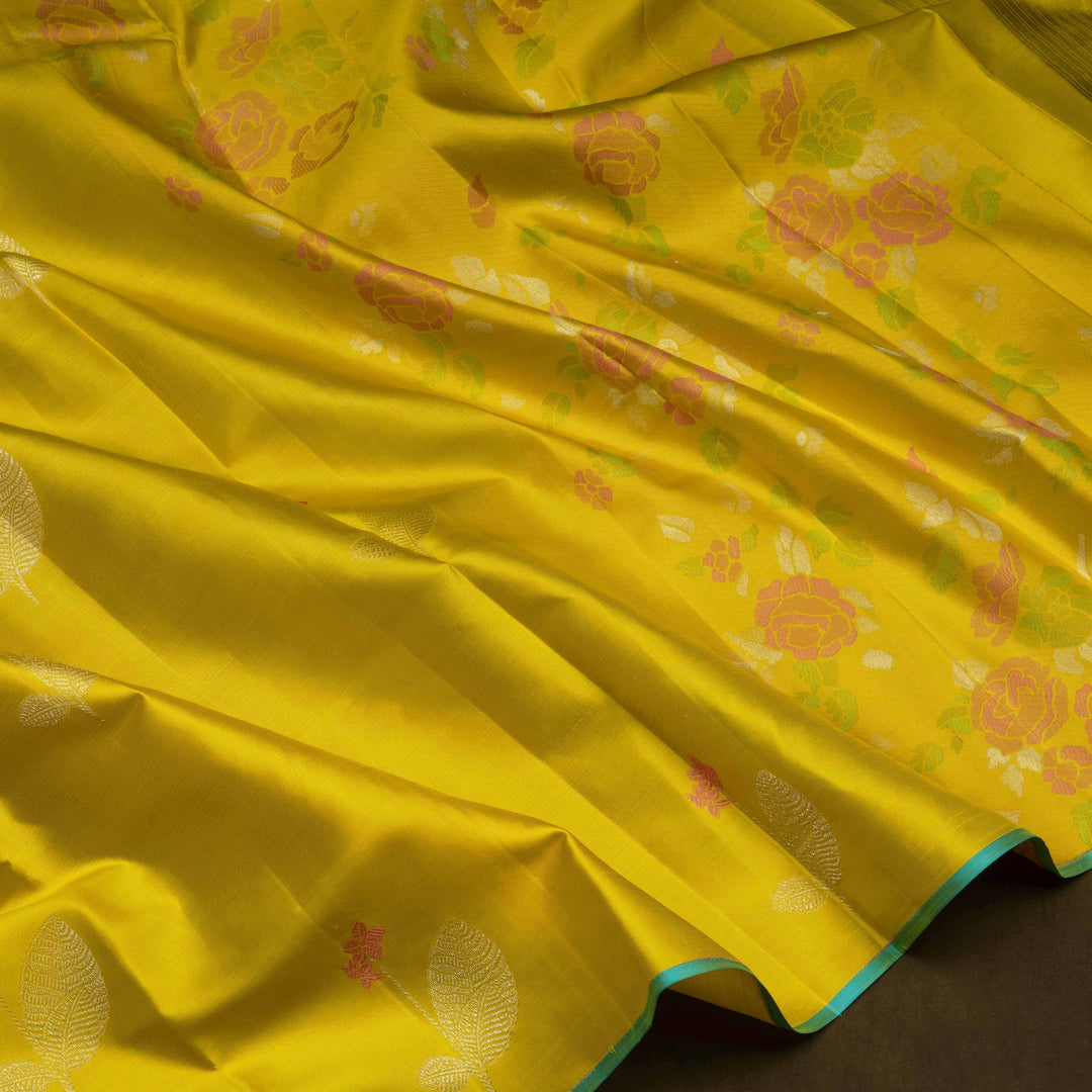 Lime green handwoven Kanjivaram silk saree with floral and leaf motifs, rose design pallu, borderless style, paired with light blue blouse with silver zari stripes.