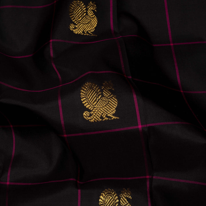 Black handwoven Kanjivaram silk saree with magenta checks, annam and chakram motifs, and pink pallu with gold zari chevron and leaf designs, paired with magenta blouse.