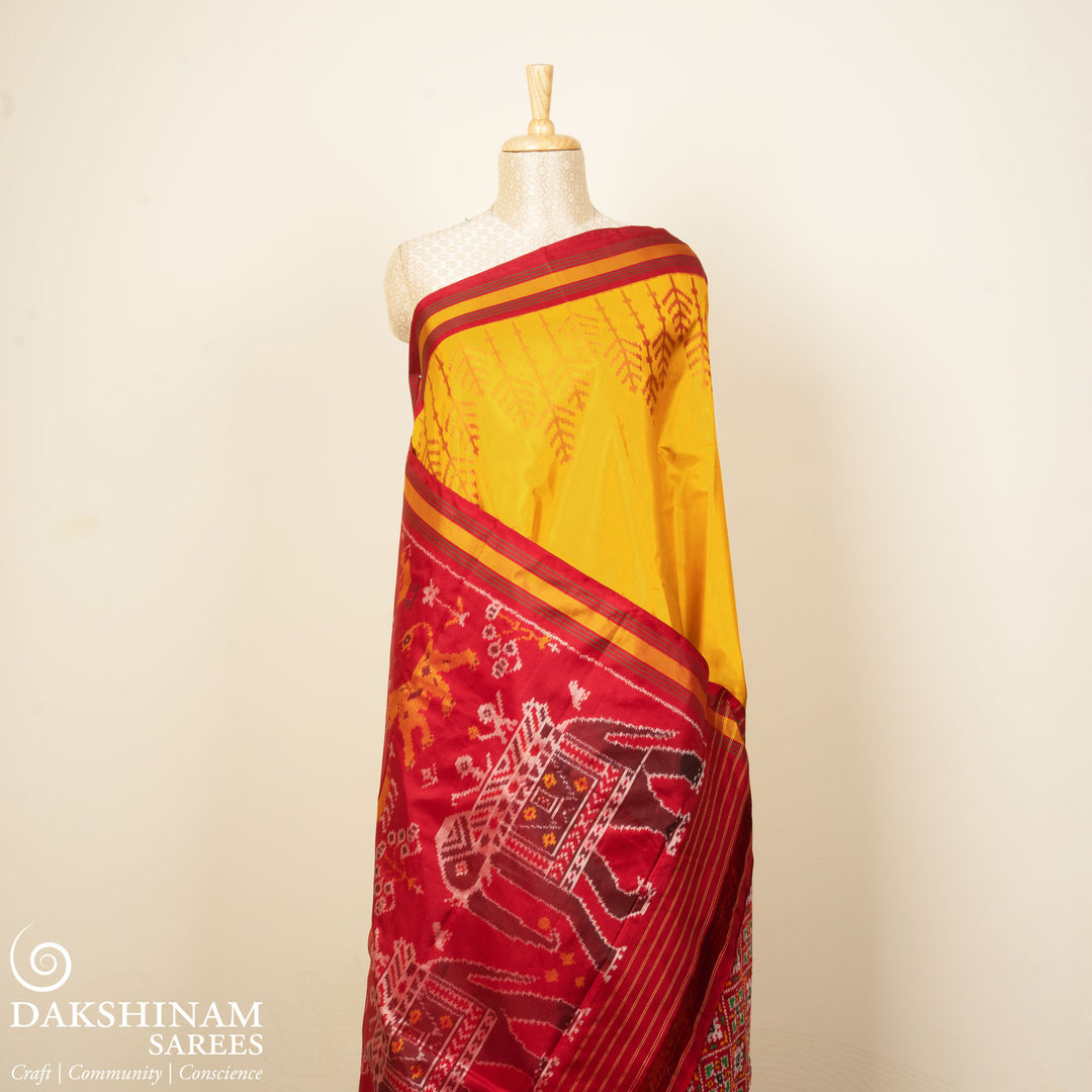 Yellow Ikat silk saree with red border accents, green and yellow border lines and red pallu with animal and human motifs, paired with red ikat blouse.