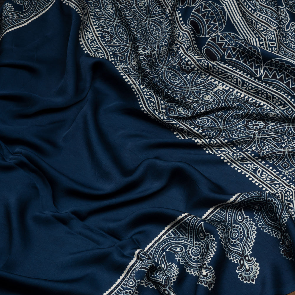 Blue handwoven modal silk cotton saree with plain blue body, Ajrakh printed border, gold zari pallu, paired with a blue Ajrakh design blouse.