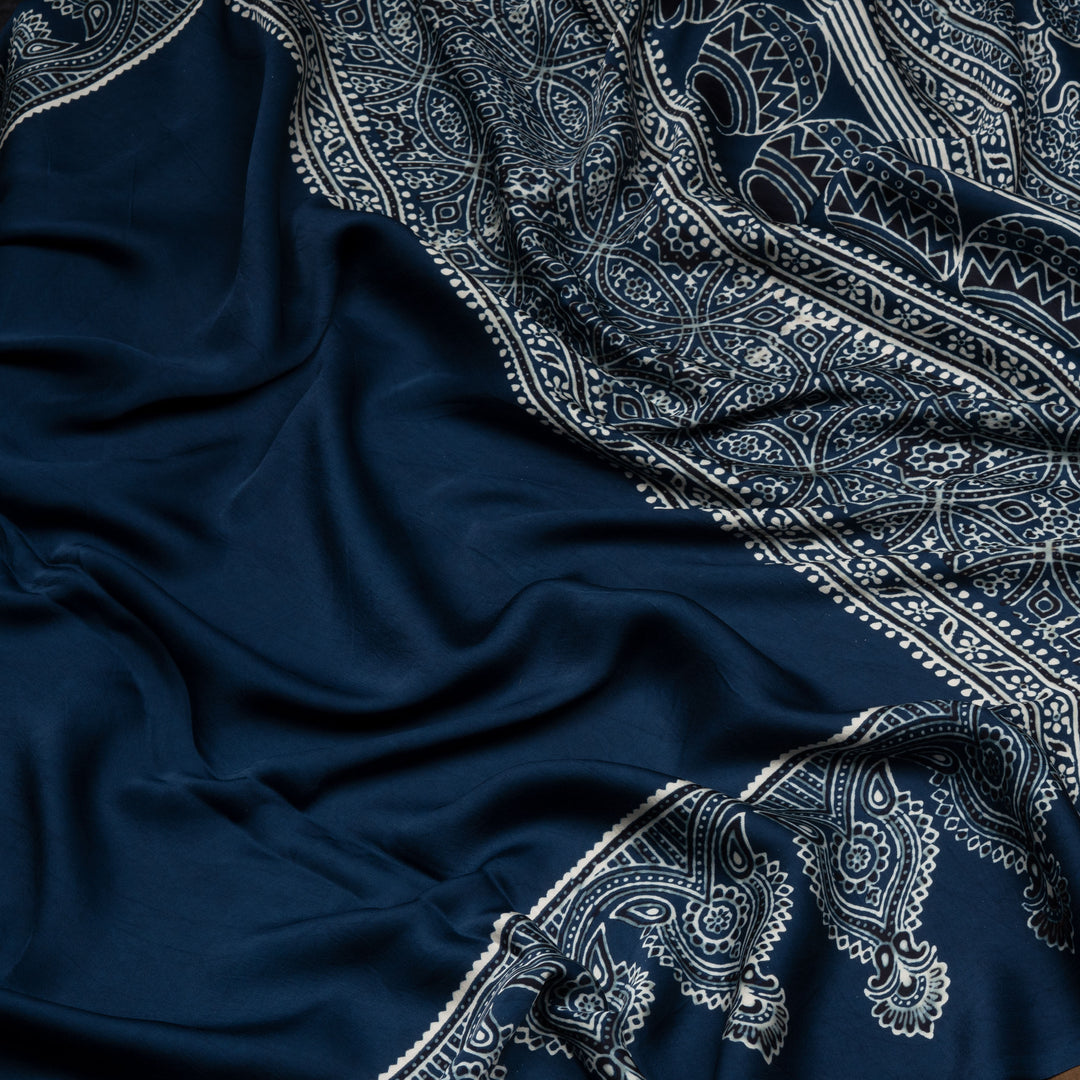 Blue handwoven modal silk cotton saree with plain blue body, Ajrakh printed border, gold zari pallu, paired with a blue Ajrakh design blouse.