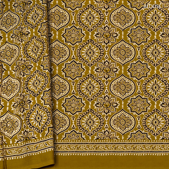 Mustard handwoven modal silk saree with floral motifs on body, Ajrakh printed border, gold zari pallu, paired with a mustard Ajrakh design blouse.