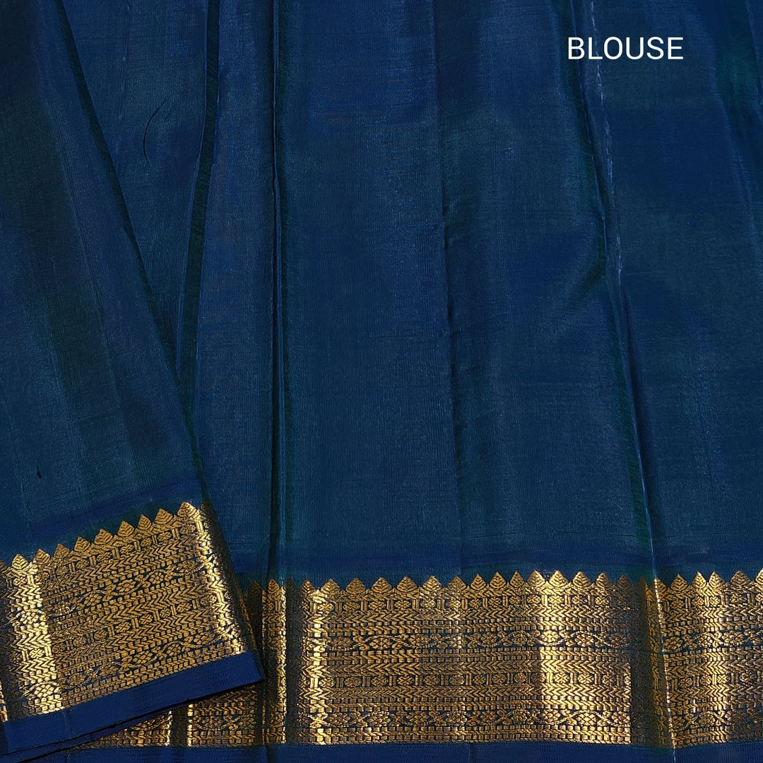 Cream Kanjivaram silk saree with chakram buttas, peacock blue border featuring chevron, rudraksham and floral lines, paired with plain blue blouse.