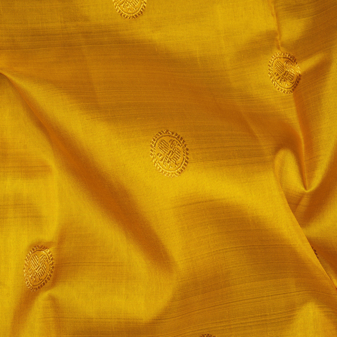 Yellow Kanjivaram silk saree with mayil buttas, pink korvai border featuring chakram and mango motifs, paired with plain pink blouse.