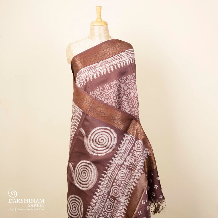 Brown handwoven silk cotton saree with batik design, gold zari floral border and artistic pallu