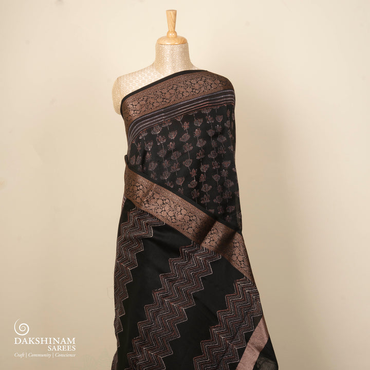 Black Chanderi silk cotton saree with white lotus floral print, gold zari border and orange striped pallu