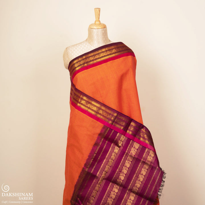 Orange Gadwal cotton saree with white checks, magenta silk border, gold zari floral motifs and striped pallu