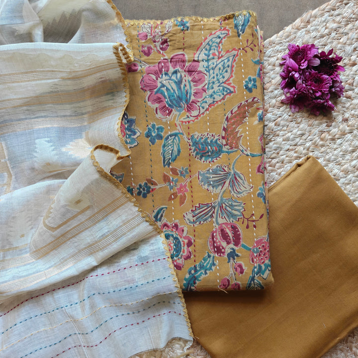 Premium mustard pure cotton 3-piece suit set featuring elegant floral prints with vertical Kantha stitch detailing and hand embroidery on the top. Paired with a plain mustard bottom and a contrasting grey dupatta, this daily wear ethnic outfit offers comfort with timeless style.