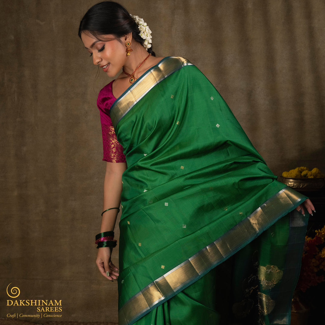 Green soft silk saree with small all-over buttas, peacock green border featuring gold zari Bavanchi designs and silver zari chevron edges, Rettaberunda motif pallu and matching blouse.