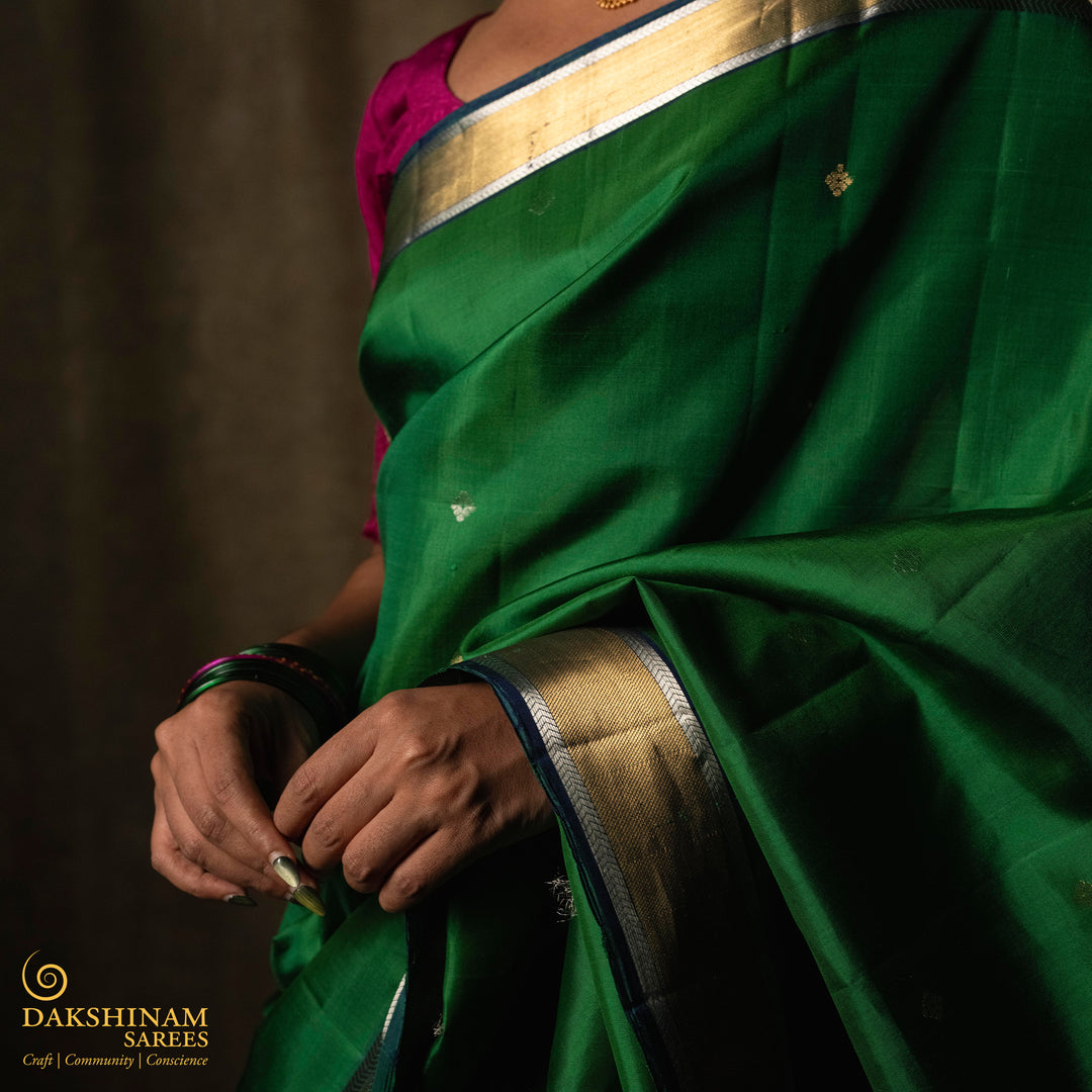 Green soft silk saree with small all-over buttas, peacock green border featuring gold zari Bavanchi designs and silver zari chevron edges, Rettaberunda motif pallu and matching blouse.