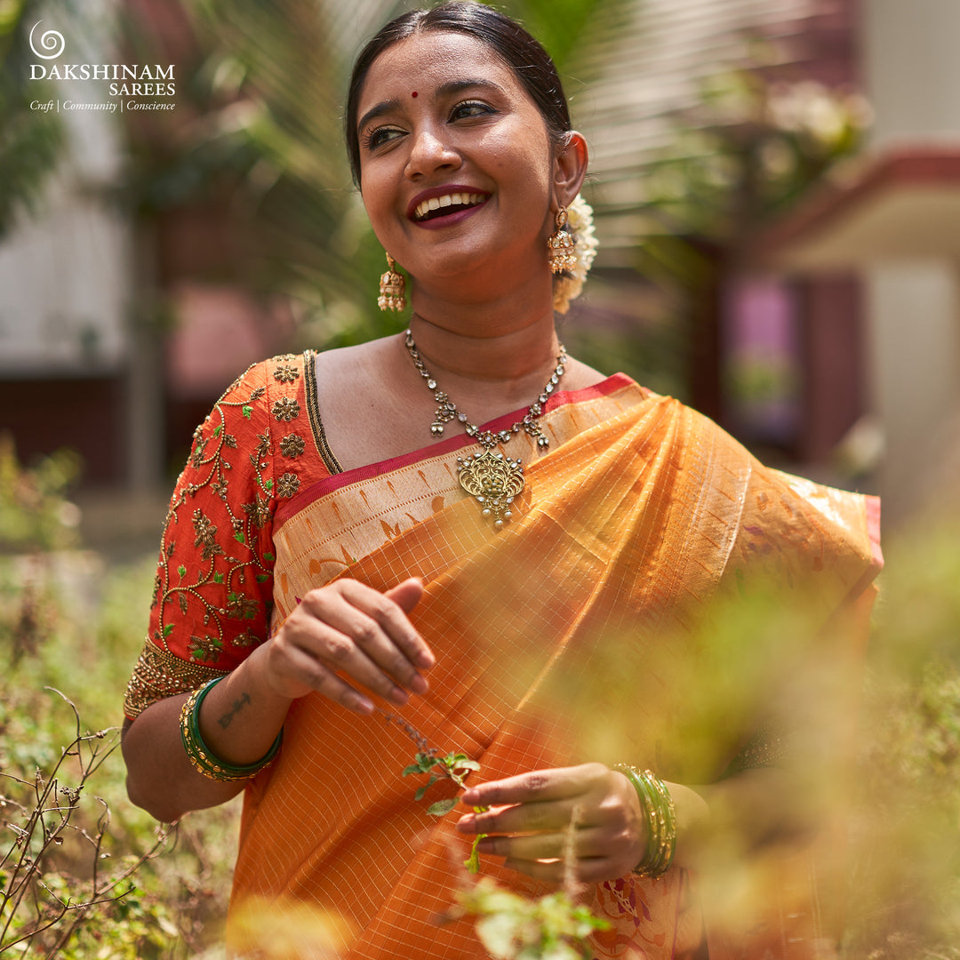 Orange Kanjivaram silk saree with checkered body, Paithani lotus vine and parrot border, pink selvedge and traditional pallu.