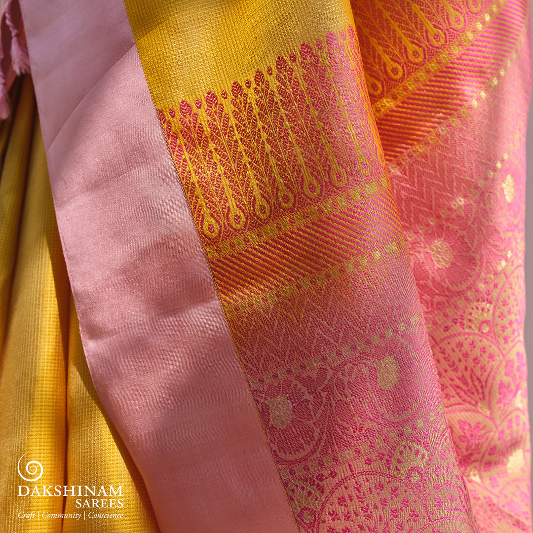 Yellow soft silk saree with self textured body and baby pink pallu with floral vine and lotus zari design