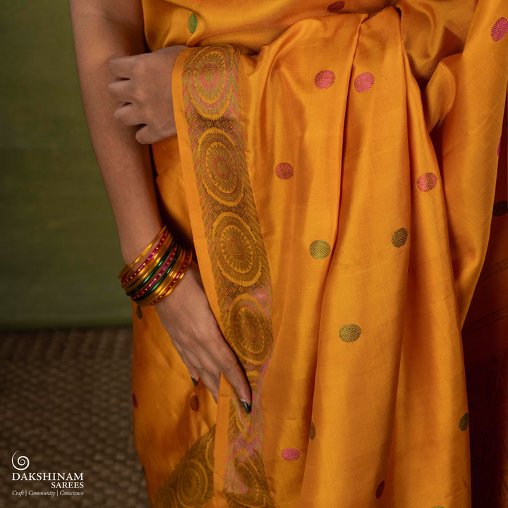 Yellow Kanjivaram silk saree with multicolor zari, red and green rudraksham buttas, green and red chakram border, floral pallu and plain yellow blouse with running border.