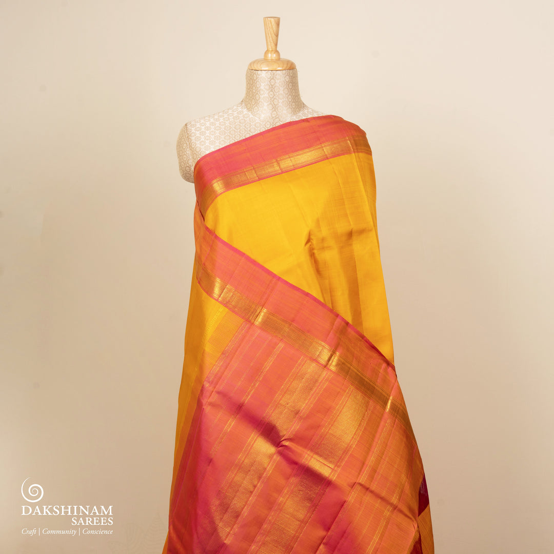 Yellow handwoven Kanjivaram silk saree with pink border, gold zari and contrast pallu