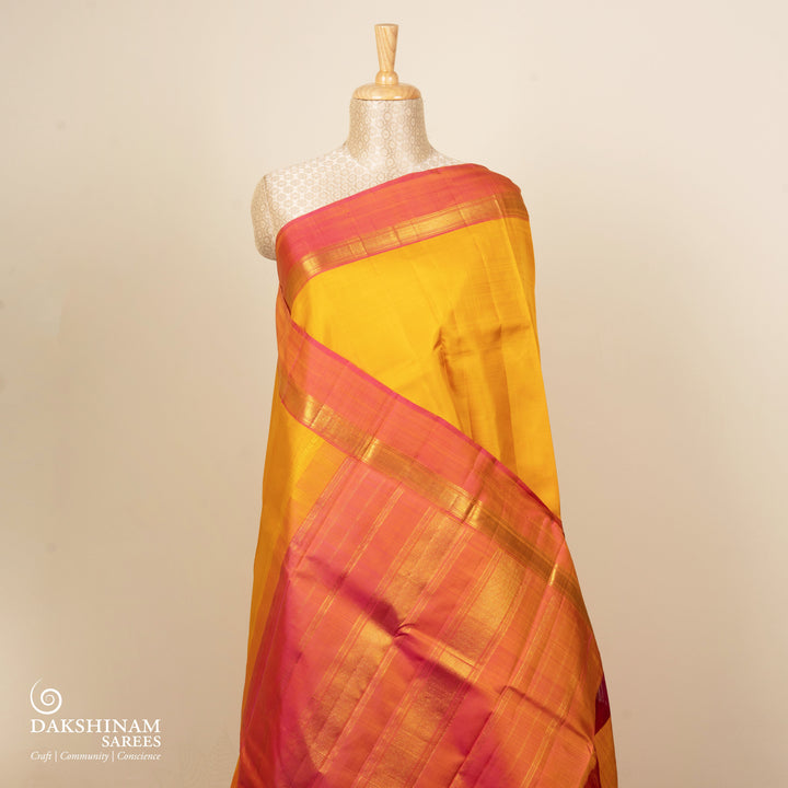 Yellow handwoven Kanjivaram silk saree with pink border, gold zari and contrast pallu