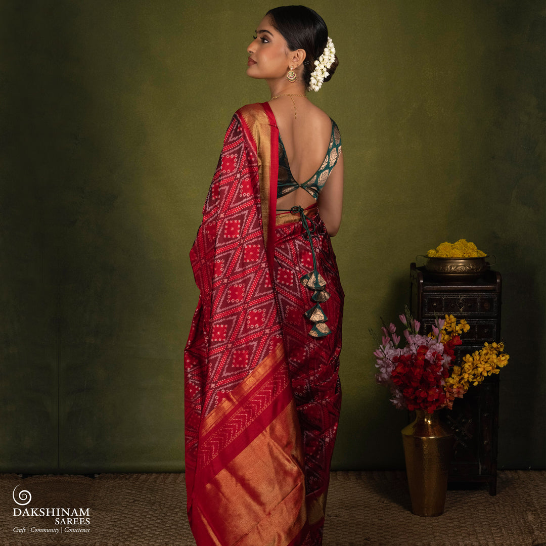 Red Ikat saree featuring maroon and grey diamond-shaped designs, gold zari border, chevron panel pallu with temple design, paired with a plain red blouse.