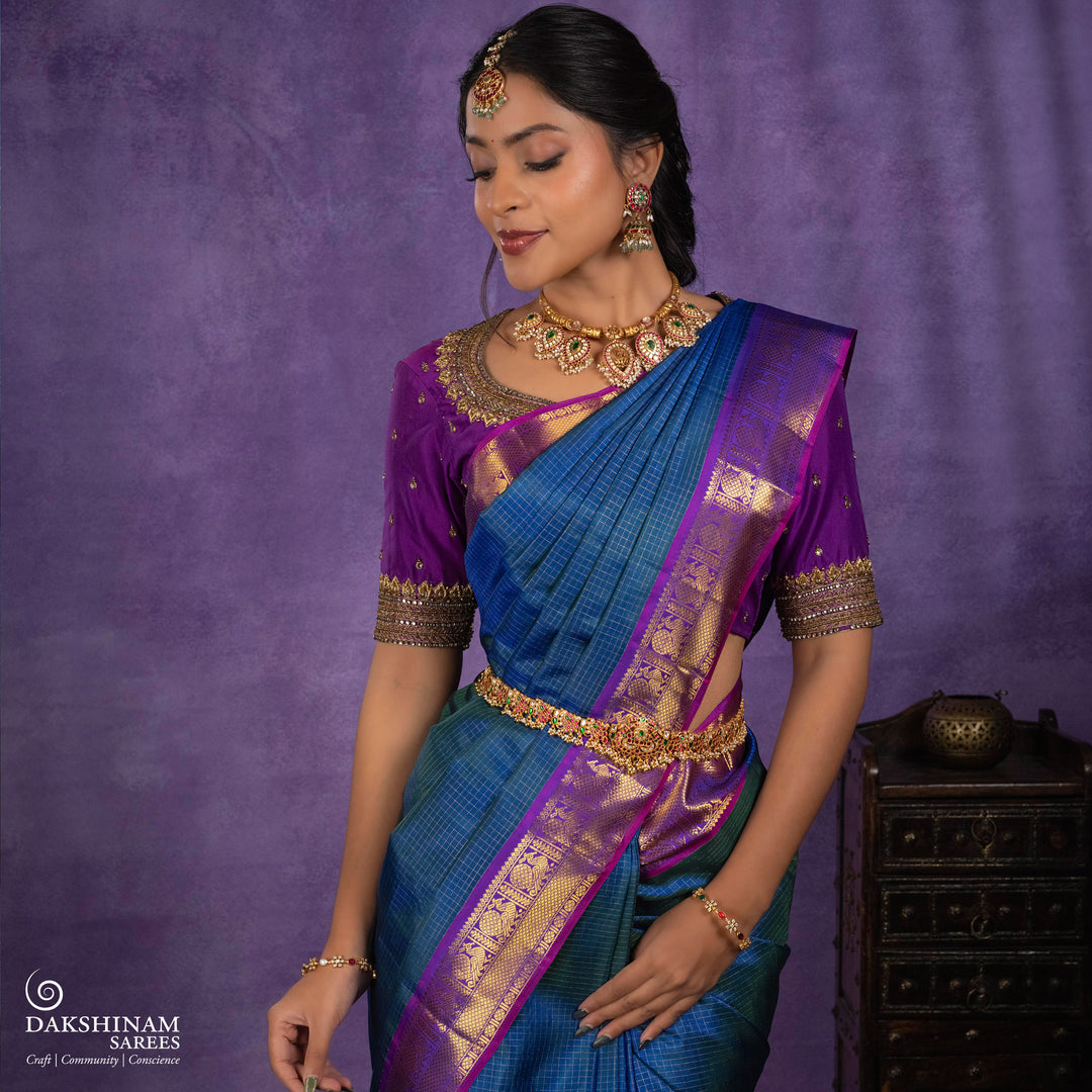 Peacock blue Korvai Kanjivaram silk saree with gold zari Vairaoosi checks, magenta contrast border, peacock motifs, diamond panel and striped pallu, paired with magenta blouse.