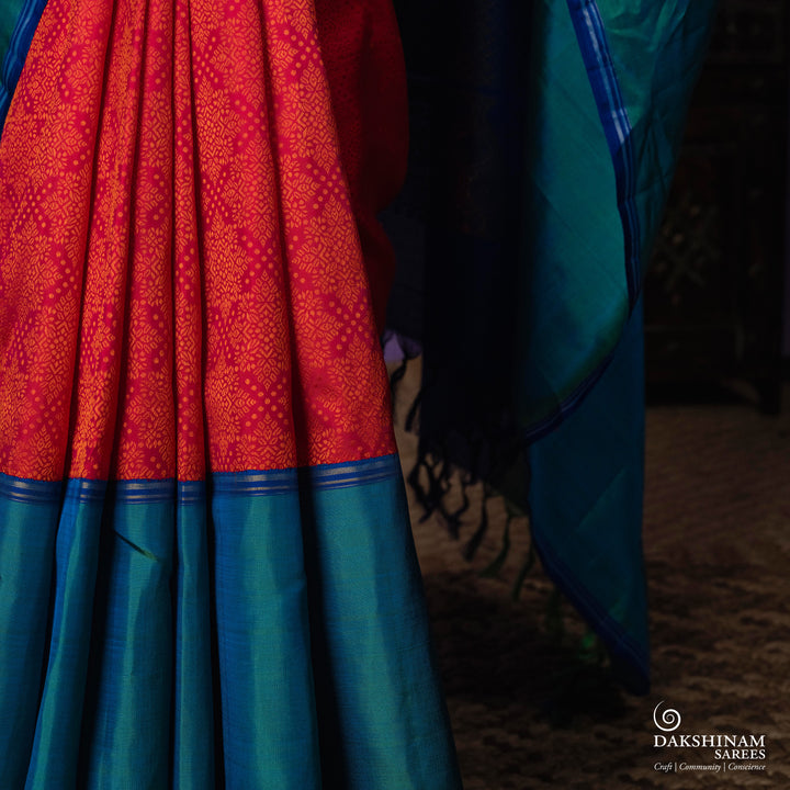 Orange no-zari Kanjivaram silk saree with light orange thread detailing, peacock green long border with silver zari lines, peacock blue pallu and matching blue blouse.
