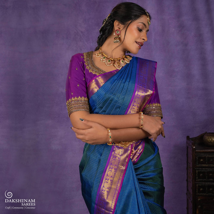 Peacock blue Korvai Kanjivaram silk saree with gold zari Vairaoosi checks, magenta contrast border, peacock motifs, diamond panel and striped pallu, paired with magenta blouse.