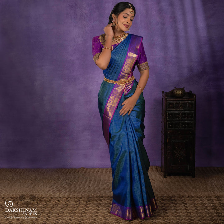 Peacock blue Korvai Kanjivaram silk saree with gold zari Vairaoosi checks, magenta contrast border, peacock motifs, diamond panel and striped pallu, paired with magenta blouse.